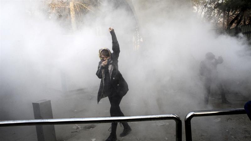 A university student attends a protest inside Tehran University while a smoke grenade is thrown by anti-riot Iranian police on December 30, 2017 [AP]