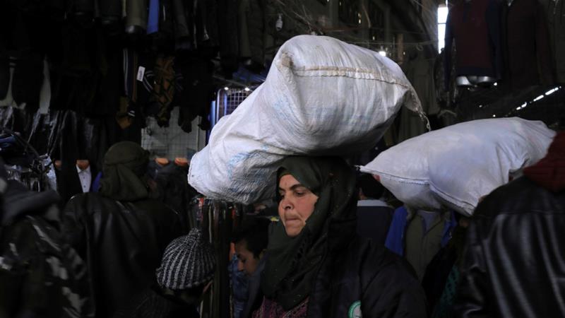 Una mujer lleva una bolsa llena de artículos en su cabeza en un zoco en la ciudad de Manbij [Rodi Said / Reuters]