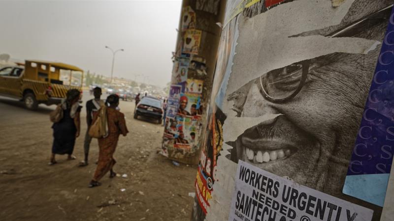 The face of incumbent President Buhari is seen on a partially-ripped campaign poster on the pillars of a highway bridge in the capital, Abuja, Nigeria [Ben Curtis/AP]