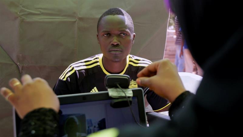 A man looks into the camera as an official collects data as part of the 2017 general elections voter registration exercise in Nairobi, Kenya on January 16, 2017 [File:Thomas Mukoya/Reuters] 