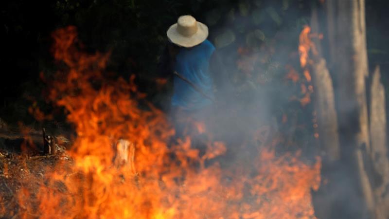 A man works in a burning tract of Amazon jungle as it is being cleared by loggers and farmers in Iranduba, Amazonas state [Bruno Kelly/Reuters]