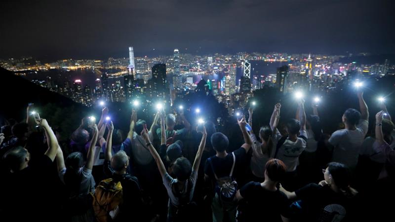 Demonstrators hold up their mobile phones as they form a human chain at the Peak, a tourist spot in Hong Kong [Kin Cheung/AP]