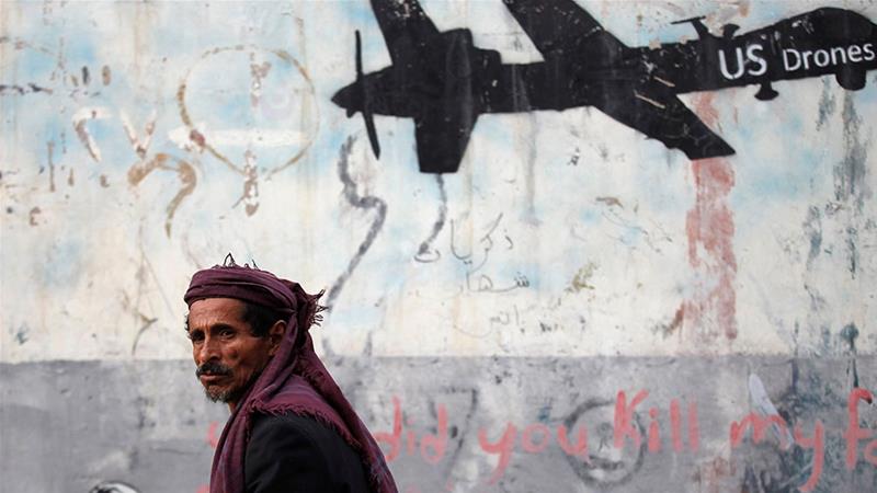 A man walks past graffiti that denounces strikes by US drones in Yemen and that is painted on a wall in Sanaa, Yemen [File: Khaled Abdullah/Reuters]