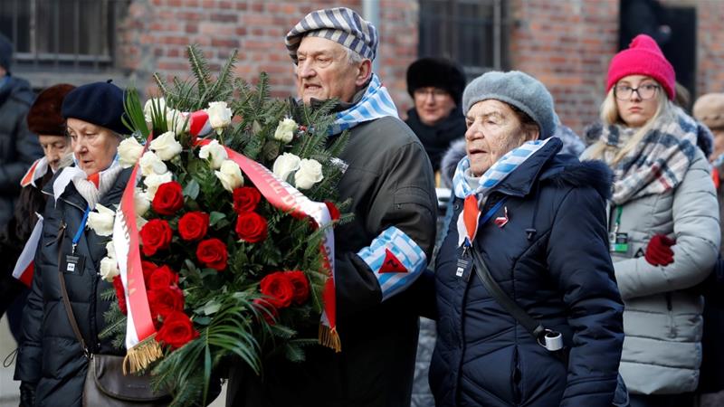 Los sobrevivientes llevan una corona de flores a medida que llegan para asistir a una ceremonia en el 'muro de la muerte' en el antiguo campo de concentración y exterminio nazi alemán, Auschwitz [Aleksandra Szmigiel / Reuters]