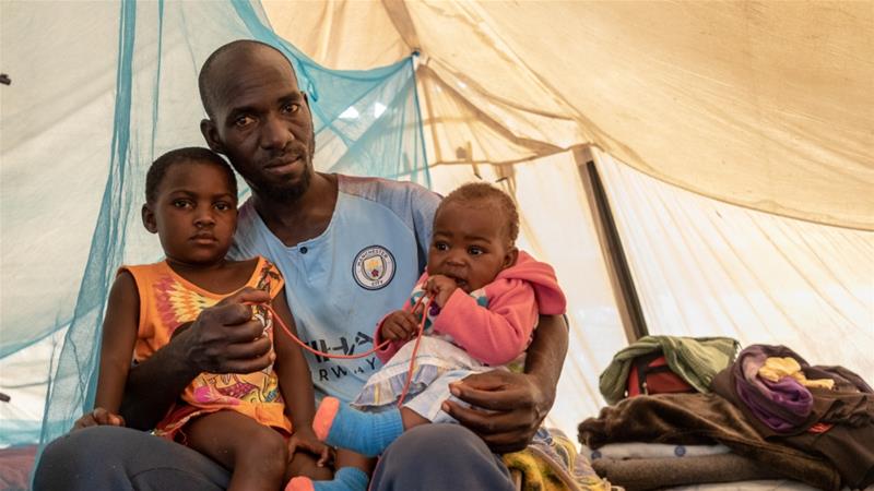 Kelvin Charamba with his daughters inside the tent the family has lived in for the past year [Tendai Marima/Al Jazeera] 