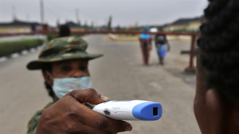 A member of the Nigerian army performs a temperature check on a visitor at the entrance of the Nigerian Army Hospital in the Yaba area of Lagos, Nigeria [File: George Osodi/Bloomberg]