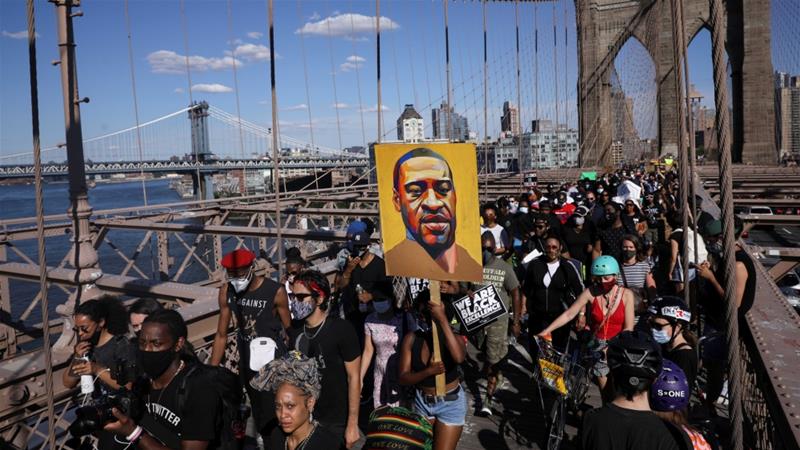 People hold signs on Brooklyn Bridge during a protest against police brutality and racism in the aftermath of the death of George Floyd in New York, US, on June 13, 2020 [Caitlin Ochs/Reuters]