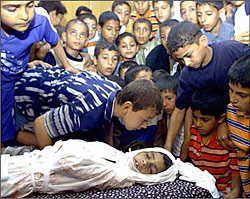 Palestinian children kiss and take a final look at the body of eight-year-old Hussein al-Matwi, who was killed by Israeli troops as he was buying sweets in al-Mughraqa village near the Jewish settlement of Netzarim in the Gaza Strip.