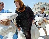 Palestinian refugees carry food distributed by the United Nations in Al-Amari camp, Ram Allah