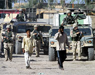 Iraqis walk in front of US soldiers in Abu Ghraib during clashes 