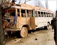An Indian army soldier standsguard beside a blast damaged bus 