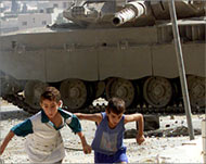 Palestinian boys run away after throwing stones at an Israeli tank 