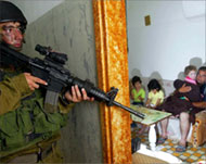 Israeli soldiers take up positioninside a home as children cower