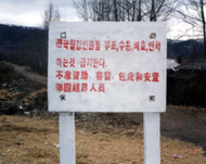 Signboard in Chinese and Korean tells people not to aid escapers