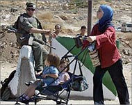 A Palestinian woman passes by an Israeli border policeman 