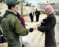 An Israeli border policeman checks a Palestinian woman's ID