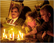 A father and daughter lightingcandles outside al-Hariri's home