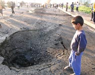 A boy looks at a crater createdby an explosion in Iraq's capital