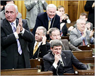 Harper (C seated) has called onMartin and the Liberals to resign