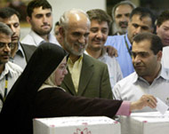 Mostafa Moin (C) watches his wifeZahra Assadirad cast her ballot