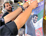 A shopkeeper tapes an Ahmadinejad poster to his window 