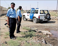 Police guard a damaged vehicle after a roadside bomb attack in Kirkuk