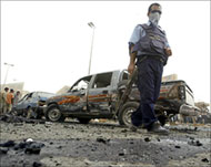 A policeman walks past the debris of a car bomb in Baghdad 