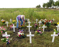 Activist Jim Goodnow puts flowers next to makeshift crosses 