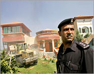 A security officer stands guard asillegal homes are pulled down