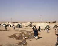 Displaced Tal Afar residents walkoutside their tents at a camp