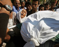 The mother (in white scarf) of one of three slain Palestinians mourns 