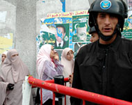 A police officer stands guard as women wait at a polling station