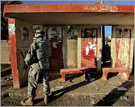 Defaced election posters point tothe threat faced by Iraqi voters