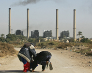 Children play as smoke rises from the Dura power station 