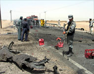 Afghan police secure a suicide car bomb blast site in Kandahar