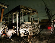 Workers inspect the wreckage of a bus burned by unidentified men