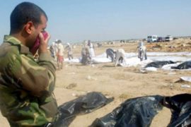 An Iraqi soldier covers his mouth and nose for the stench as Iraqi people carry unidentified dead bodies of victims killed during the Iraqi daily violence