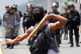Protester throws stick at riot police in Quito