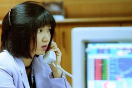 #719230: Thai broker trades on telephone behind stock prices screen, Bangkok, Thailand, photo [AP] - Riz Khan