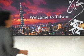 A passerby walks past a billboard welcoming tourists at Taipei's airport.