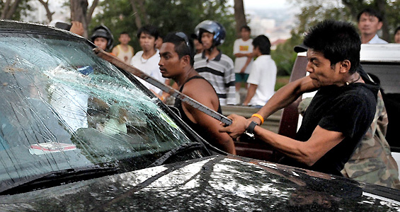 ASF1359 - PATTAYA, THAILAND : A Government supporter (R) hits a car of an opponent after a rally held by supporters of former premier Thaksin Shinawatra infront the hotel of the 14th Association of Southeast Asian Nations (ASEAN) Summit and Related Summits in Pattaya on April 10, 2009. Thai protesters pushed through security at the summit of Asian leaders forcing their campaign to topple Prime Minister Abhisit Vejjajiva into the international spotlight. AFP PHOTO / NICOLAS ASFOURI