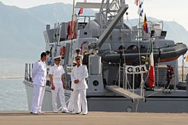 Libyan naval officers stand in front of one of three new patrol ships donated by the Italian government to Libya