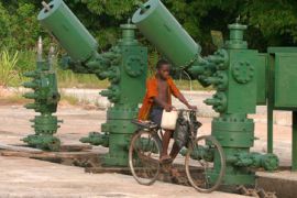 Boy rides bicycle past oil pumps in Niger Delta