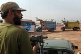 Pakistani soldier overlooks displaced Pakistani as they return to Swat