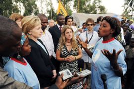 US Secretary of State Hillary Clinton (2-L) listens to a speaker during a visit to a refugee camp on the outskirts of Goma