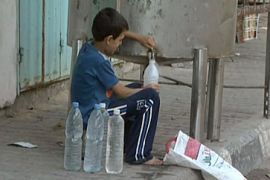 Palestinian boy filling water bottles