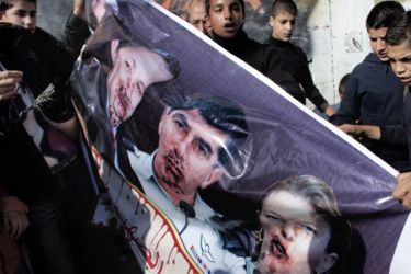 Palestinian children hold a poster depicting the blood-smeared faces of Israeli Pols