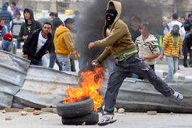A Palestinian youth throws a stone towards Israeli border police during clashes in Hebron