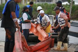 Workers move oil boom