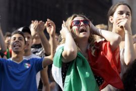 Italian soccer fans react while watching a live telecast of